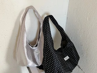 Two soft shoulder bags, one cream and one black with a dotted pattern