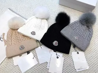 Four knitted beanies with pom-poms, in cream, white, black and grey