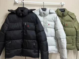 Three padded winter jackets on a rail, in black, pale grey and olive