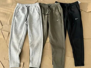 Three pairs of cuffed joggers laid side by side in grey, olive and black